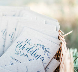 blue wedding invitations in a basket