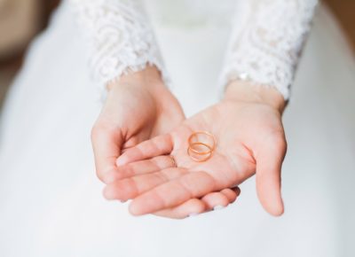 bride holding two gold wedding rings