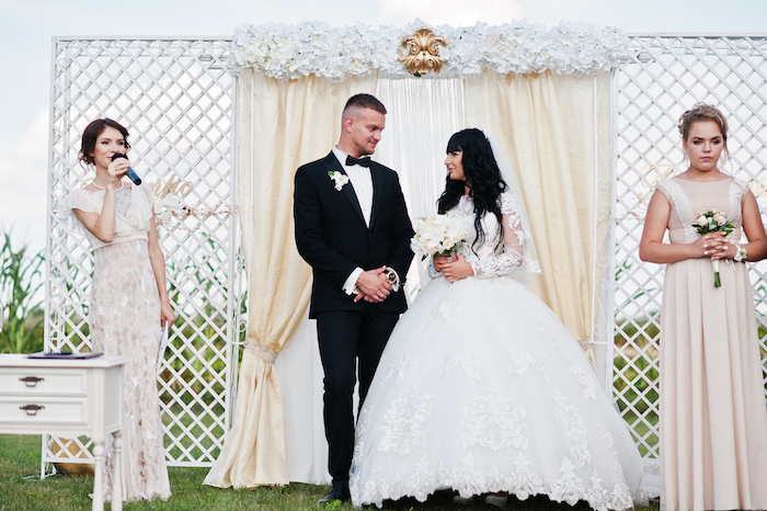 Bride and groom stand next to the master of ceremonies