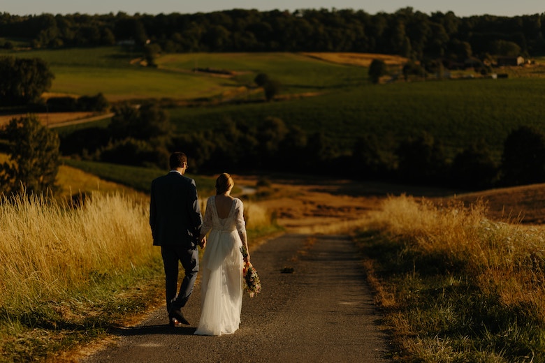 A young newlywed couple walking down the road into the sunset