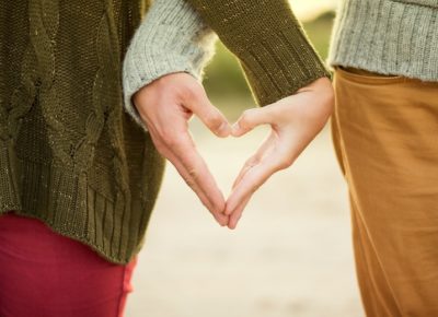 young couple making a heart shape with their hands