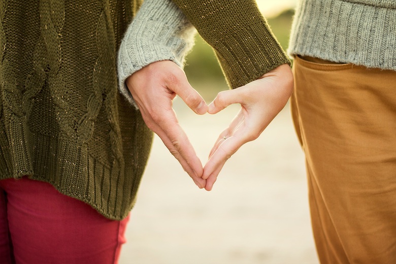 young couple making a heart shape with their hands