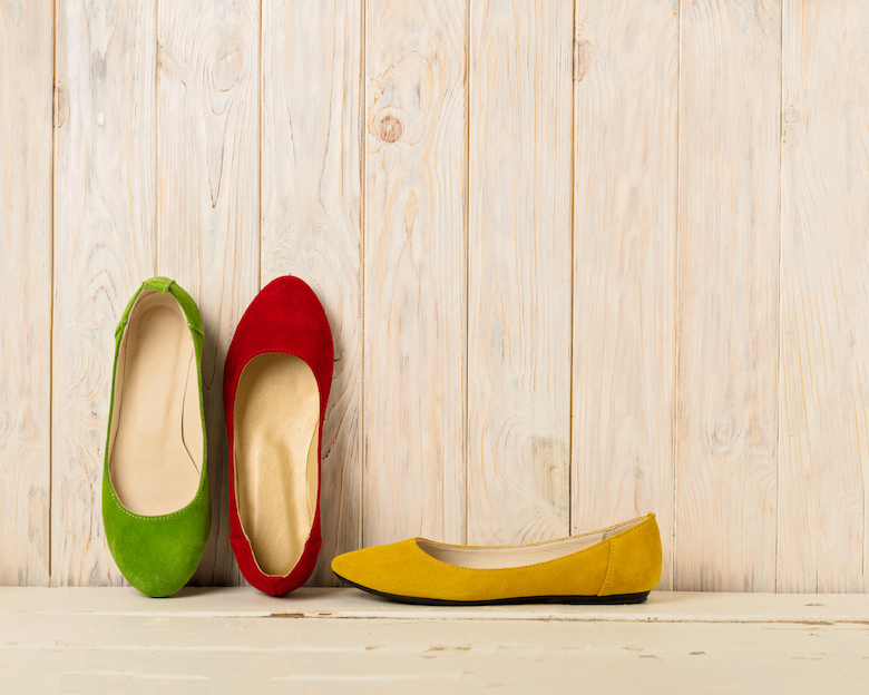 Red green and yellow women's shoes (ballerinas) on wooden background.