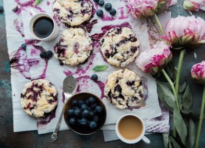 blueberry cookies and fruit spread out on a table, next to some pink purple flowers