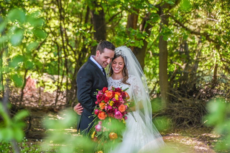 bride and groom in the forest, bride is holding a colorful bouquet of flowers