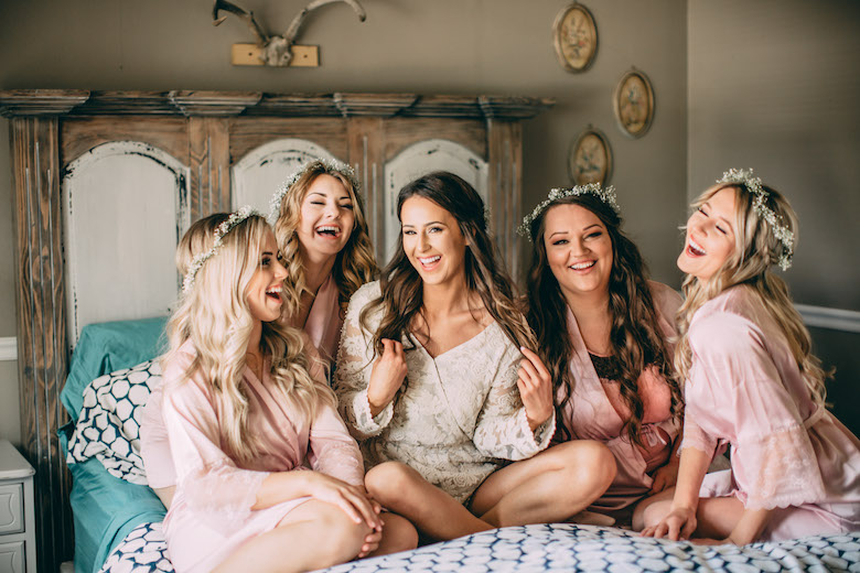 Bride and bridesmaid on bed laughing