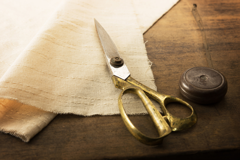 a pair of golden scissors lying on top of a piece of linen fabric