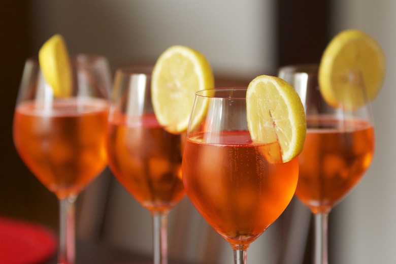 Four red bubbly cocktails with a slice of lemon