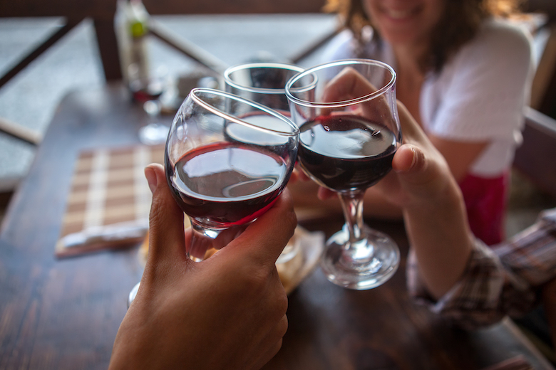 Three young friends enjoying a "cheers!" with glasses of red wine