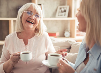 Smiling mother and daughter enjoying a cup of coffee together