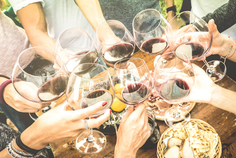 Toasting with glasses of red wine, outdoor venue