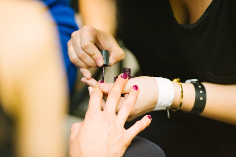 female hand getting manicured, red nail polish