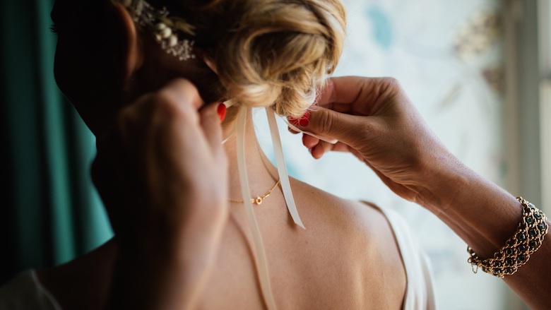 Woman getting her hair adjusted while wearing her wedding dress