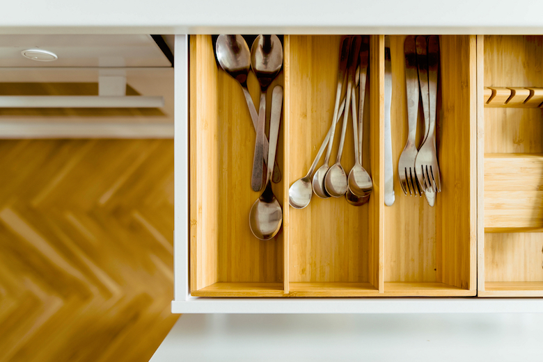 Wooden drawer filled with silverware (knives, spoons, forks)