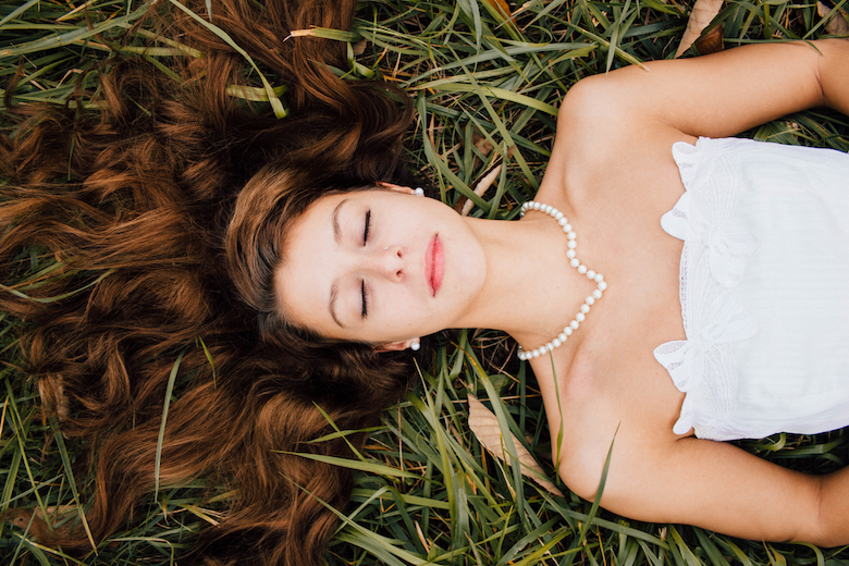 smiling young bride lying in the grass, eyes closed