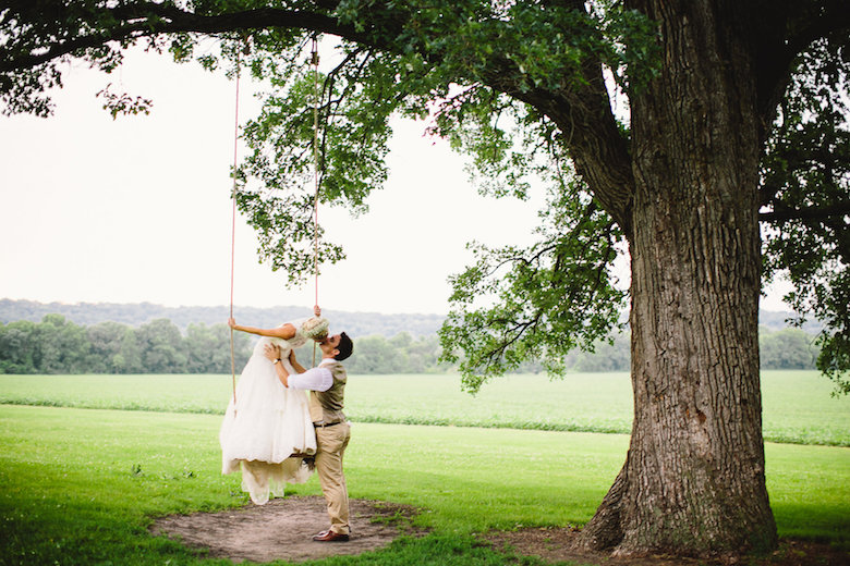 Bride and groom kissing on a tree, green grassy background
