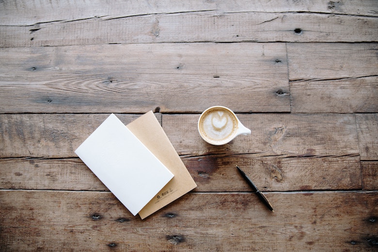 a card and a cup of coffee on a wooden table