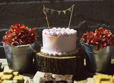photo of small cake between two red shrubs at a wedding