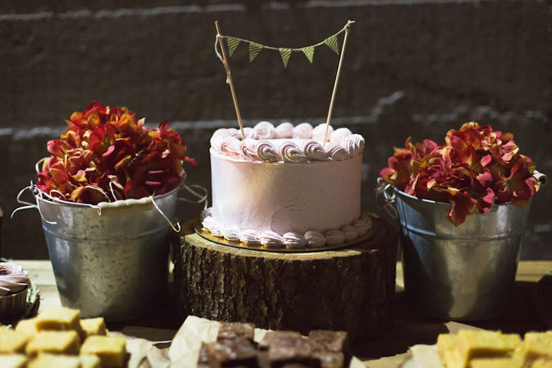 photo of small cake between two red shrubs at a wedding
