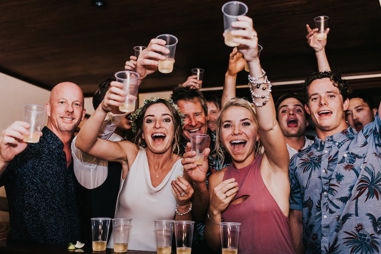 the bride and wedding guests enjoying a cheers with glasses of alcohol