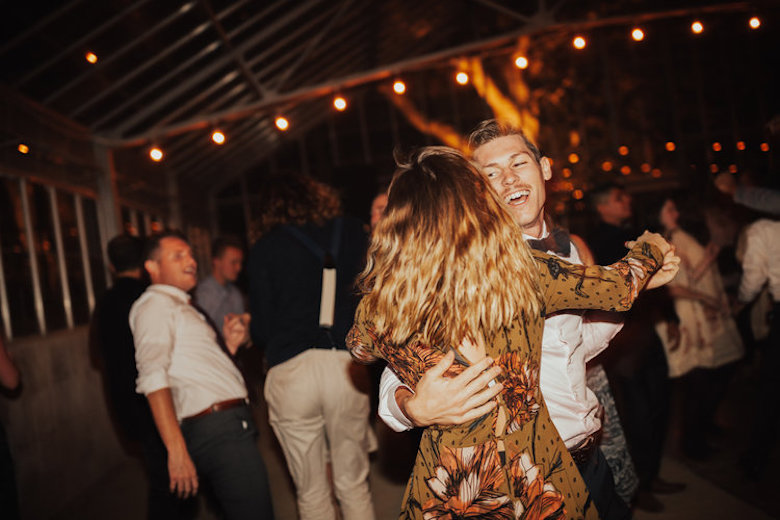 young man and woman smiling and dancing at a wedding