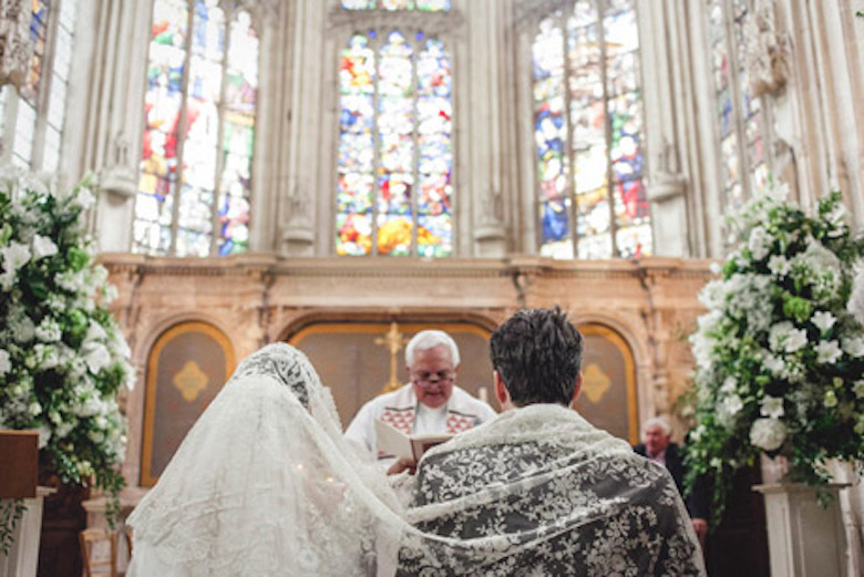 religious ceremony, bride and groom at the altar with a church officiant at the front, stained glass windows in the background