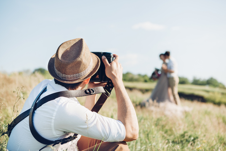 shot of a wedding photographer taking wedding photos in a grassy field
