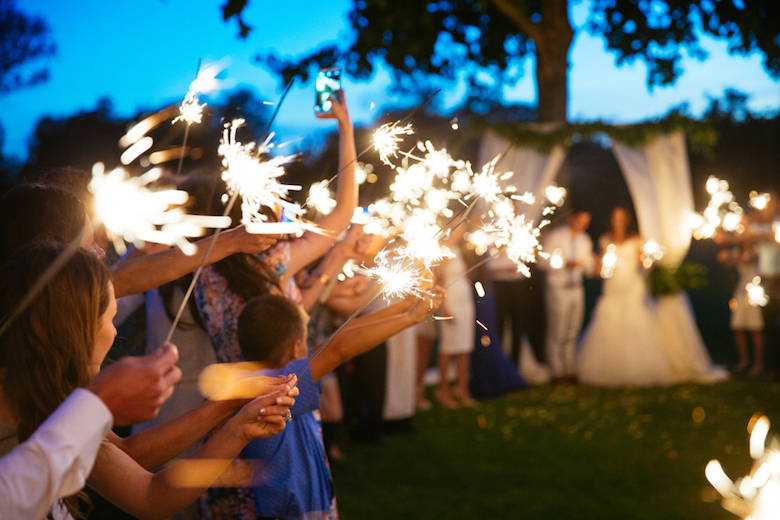 wedding attendees holding sparklers at dusk
