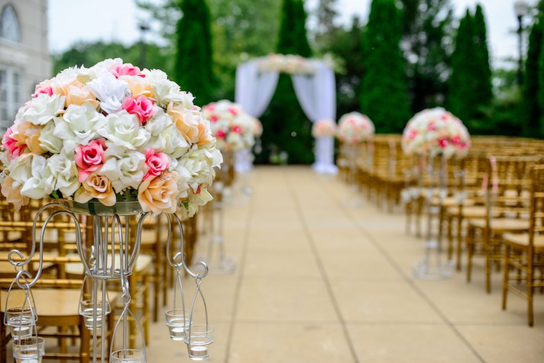 outdoor wedding venue, pink and white flowers in focus with the altar in the background