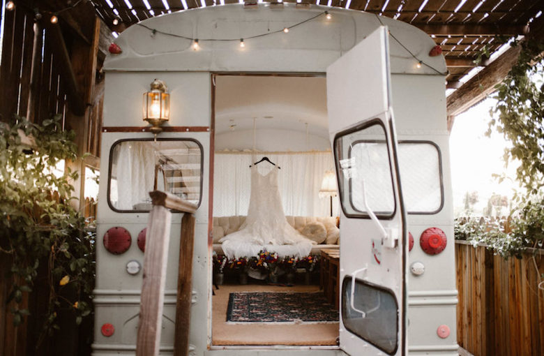 white bus with wedding dress and flowers inside, back door is open