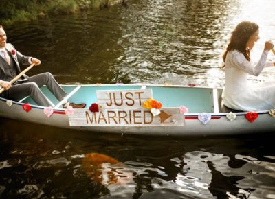 bride and groom sitting on a canoe with a just married sign in the center