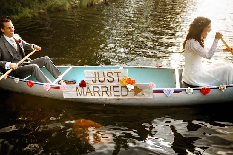 bride and groom sitting on a canoe with a just married sign in the center