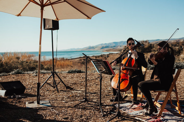 Two string musicians playing wedding music outdoors