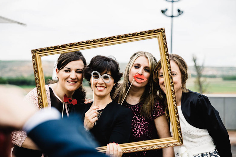 wedding guests posing inside a picture frame for a photo, silly props used
