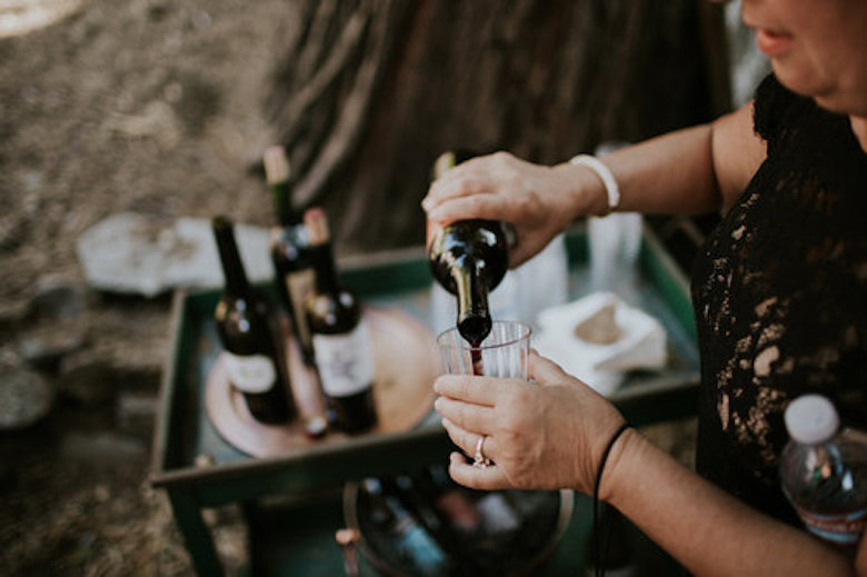 woman pouring wine into a glass at a wedding