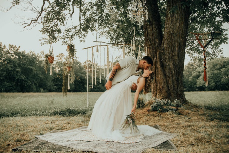 couple kissing against an old oak tree with cascading lights and a crystal chandelier