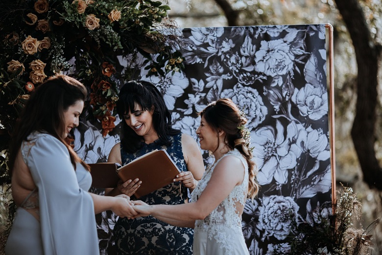 couple saying their vows against a black and white hand drawn floral artwork 