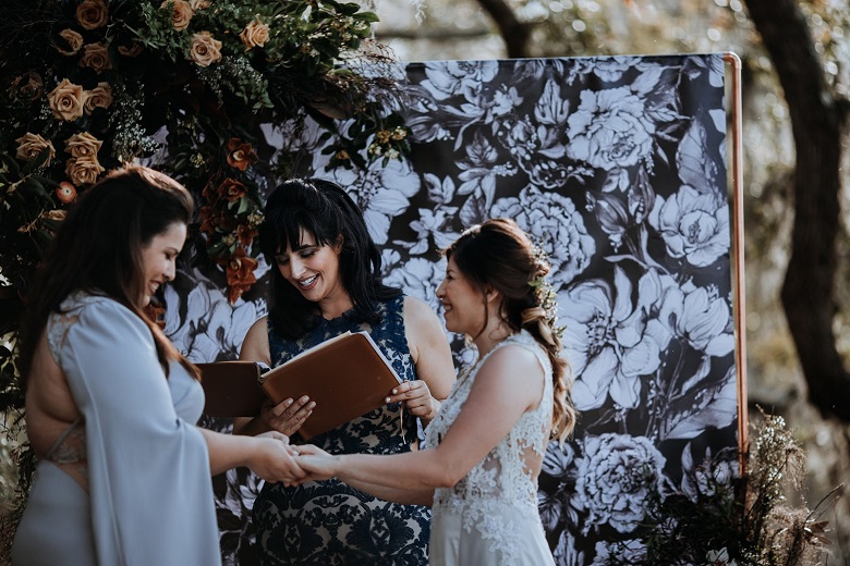 couple saying their vows against a black and white hand drawn floral artwork