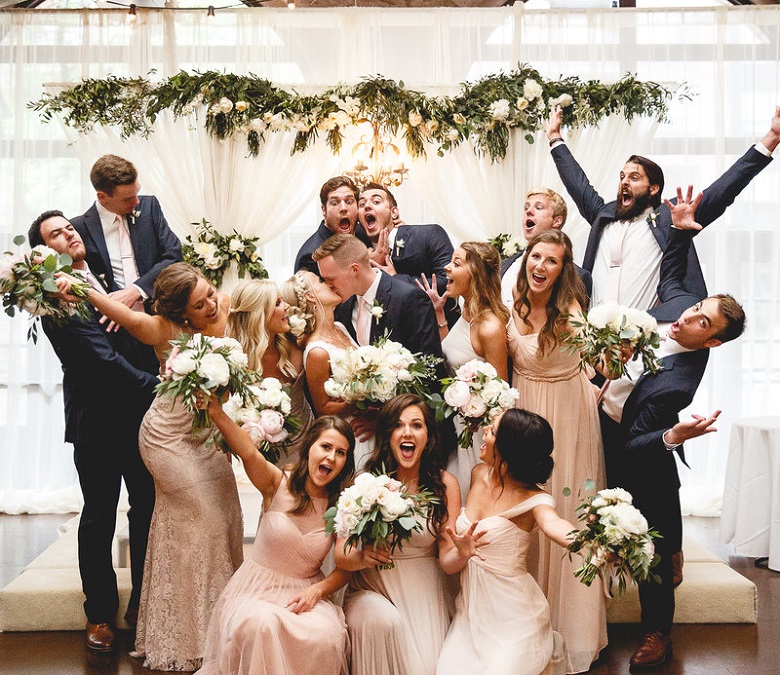 bridesmaids and groomsmen against a sheer screen fabric wedding backdrop