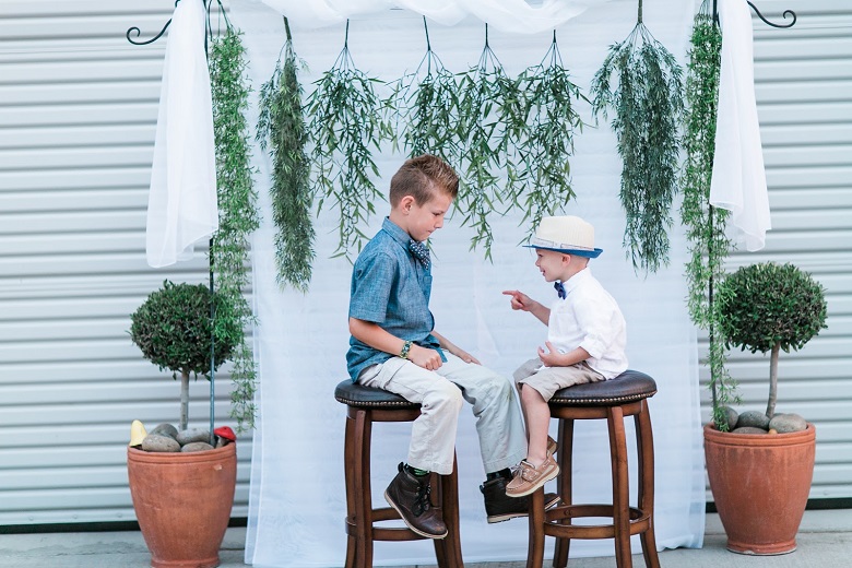 kids against a minimalist weddding backdrop with dangling greenery garlands