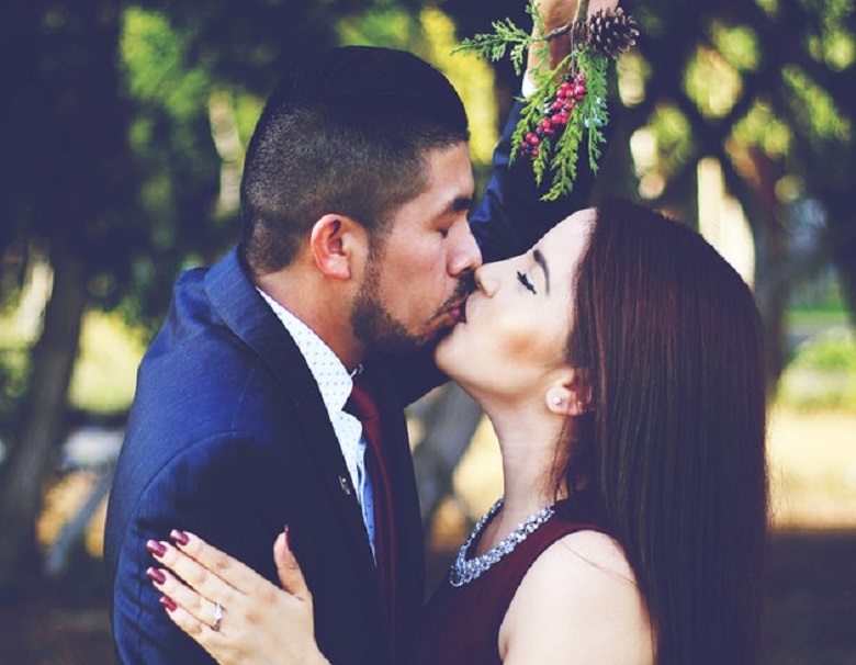 bride and groom kissing under mistletoe sprig