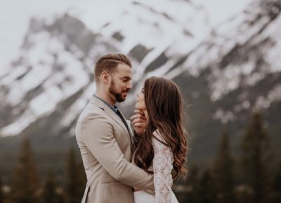 bride and groom staring lovingly into each other eyes with mountain destination wedding backdrop