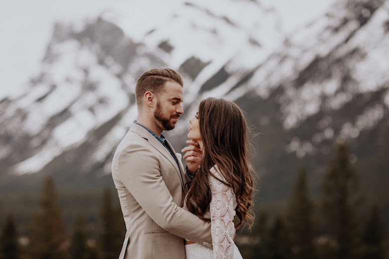 bride and groom staring lovingly into each other eyes with mountain destination wedding backdrop