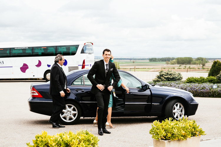 Dressed-up guests get out of an automobile, ready for the wedding