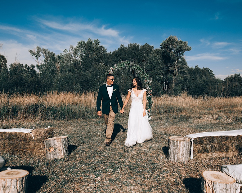 bride and groom walking down the aisle against a circled wreath backdrop