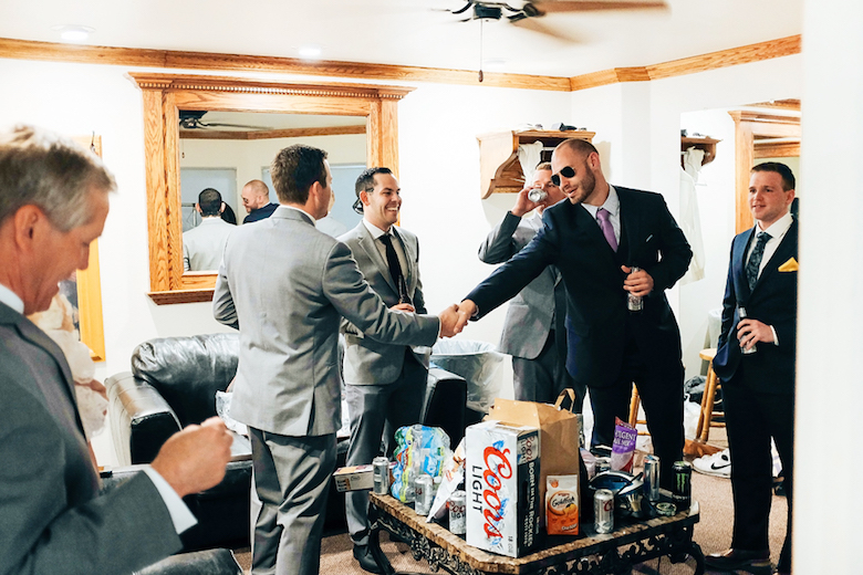 groomsmen shaking the groom's hand, indoors, drinking and preparing for the wedding