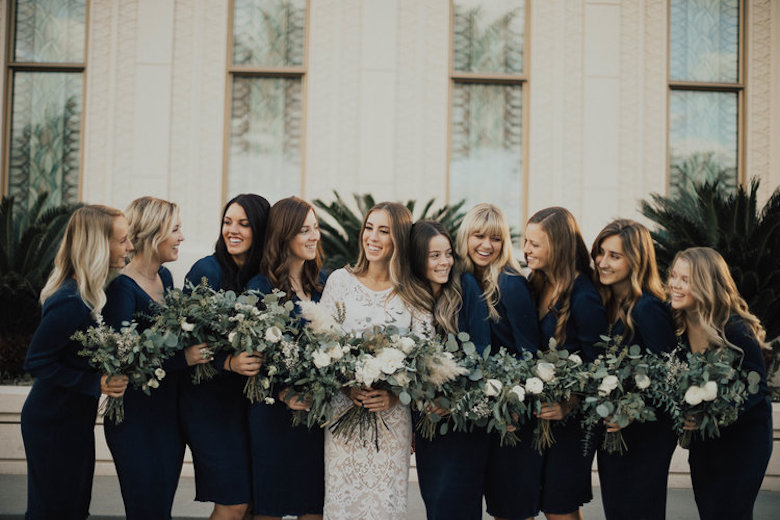 beautiful bride surrounded by bridesmaids dressed in blue holding flowers