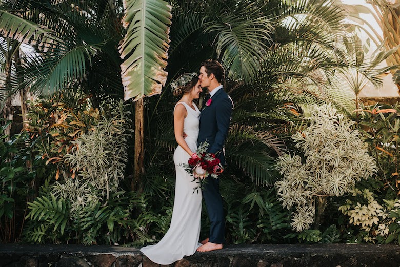 bride and groom embracing in front of exotic forest