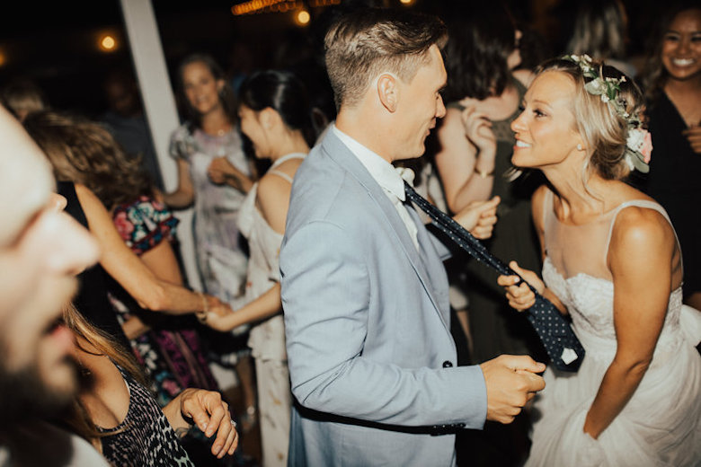 happy bride pulls the groom in by his tie, loving gaze