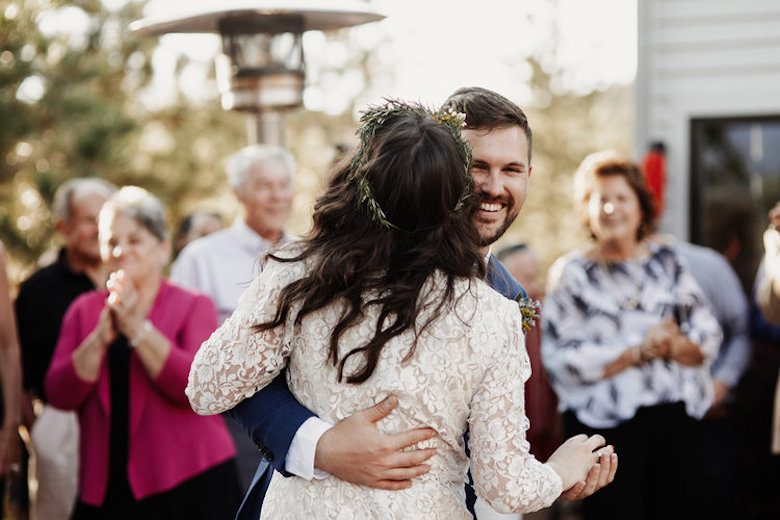 smiling groom and his lovely bride dance outside, being watched by happy onlookers